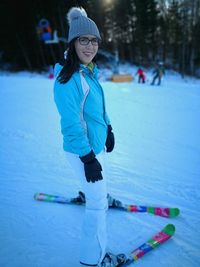Portrait of young woman snowboarding on snow covered field