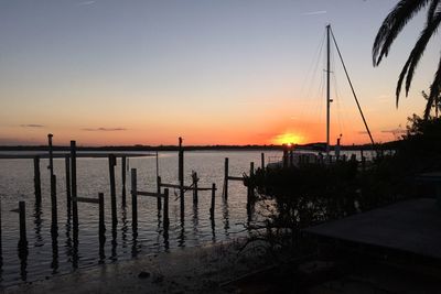 Silhouette of wooden post on beach during sunset