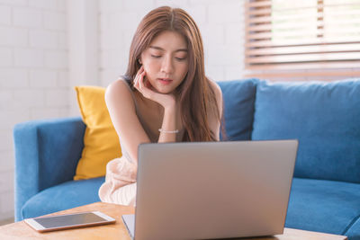 Asian woman relaxing sitting on sofa using computer notbeook at living room, 