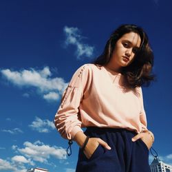 Low angle view of woman standing against blue sky