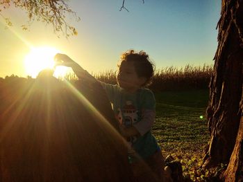Children playing on field against clear sky during sunset