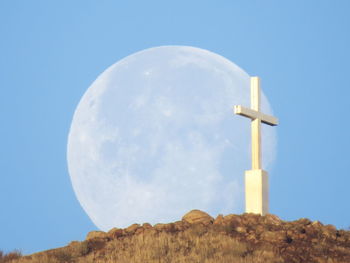 Low angle view of cross on rock against sky