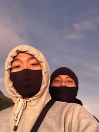 Portrait of men wearing mask against sky