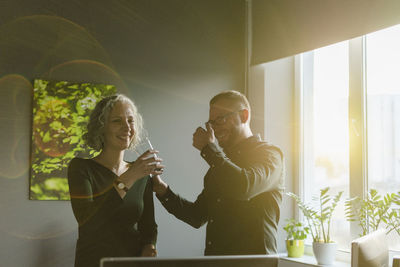 Happy businessman and businesswoman in office in backlight