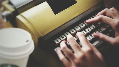 Cropped hands of woman typing on typewriter