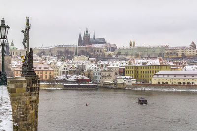 Sailboats in river against buildings in city