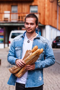 Young man holding bread while standing on street