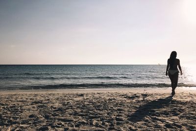 Full length of man walking on beach against clear sky