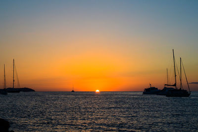 Sailboats sailing in sea against sky during sunset