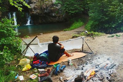 Rear view of man camping in forest