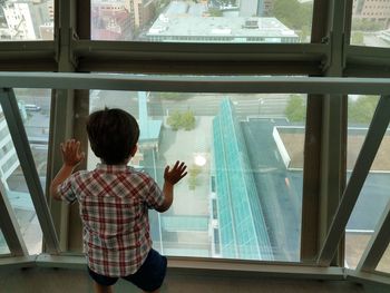 Rear view of boy standing by window