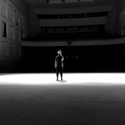 Rear view of woman standing on illuminated stage in auditorium