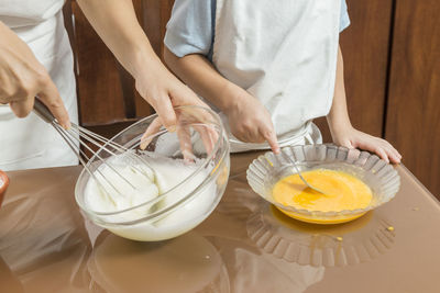 Mid section of woman and son cooking on table