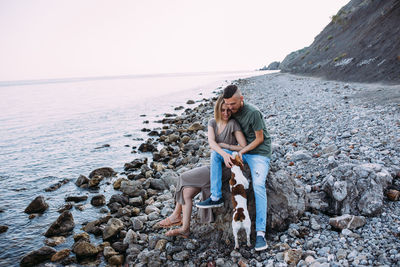 Happy couple with favourite pet. young man and woman have walk near sea.