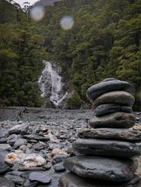 Stack of stones on rocks in water against sky