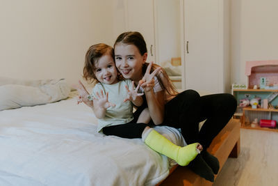 Two girls are fooling around while sitting on the bed in the morning.
