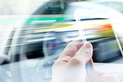 Cropped image of hand holding mobile phone in car