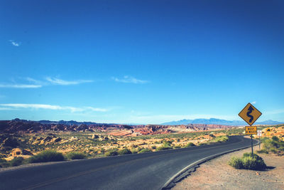 Road by landscape against blue sky