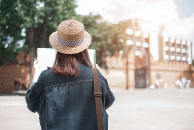 Rear view of woman standing on street in city