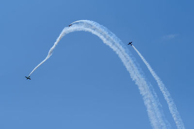 Low angle view of airshow against clear blue sky