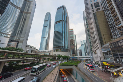 Vehicles on road amidst buildings in city against sky