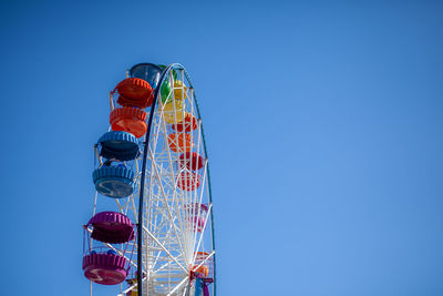 A large ferris wheel against a blue sky. booths with people go up. 