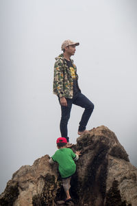 Woman standing on rock against sky