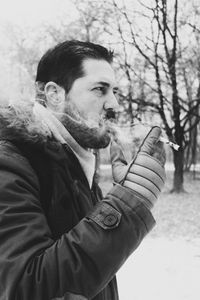 Close-up of young man holding cigarette in winter