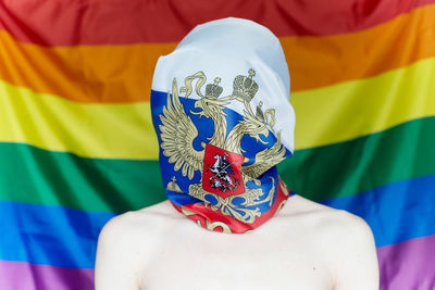 Close-up of shirtless woman standing against colorful fabric