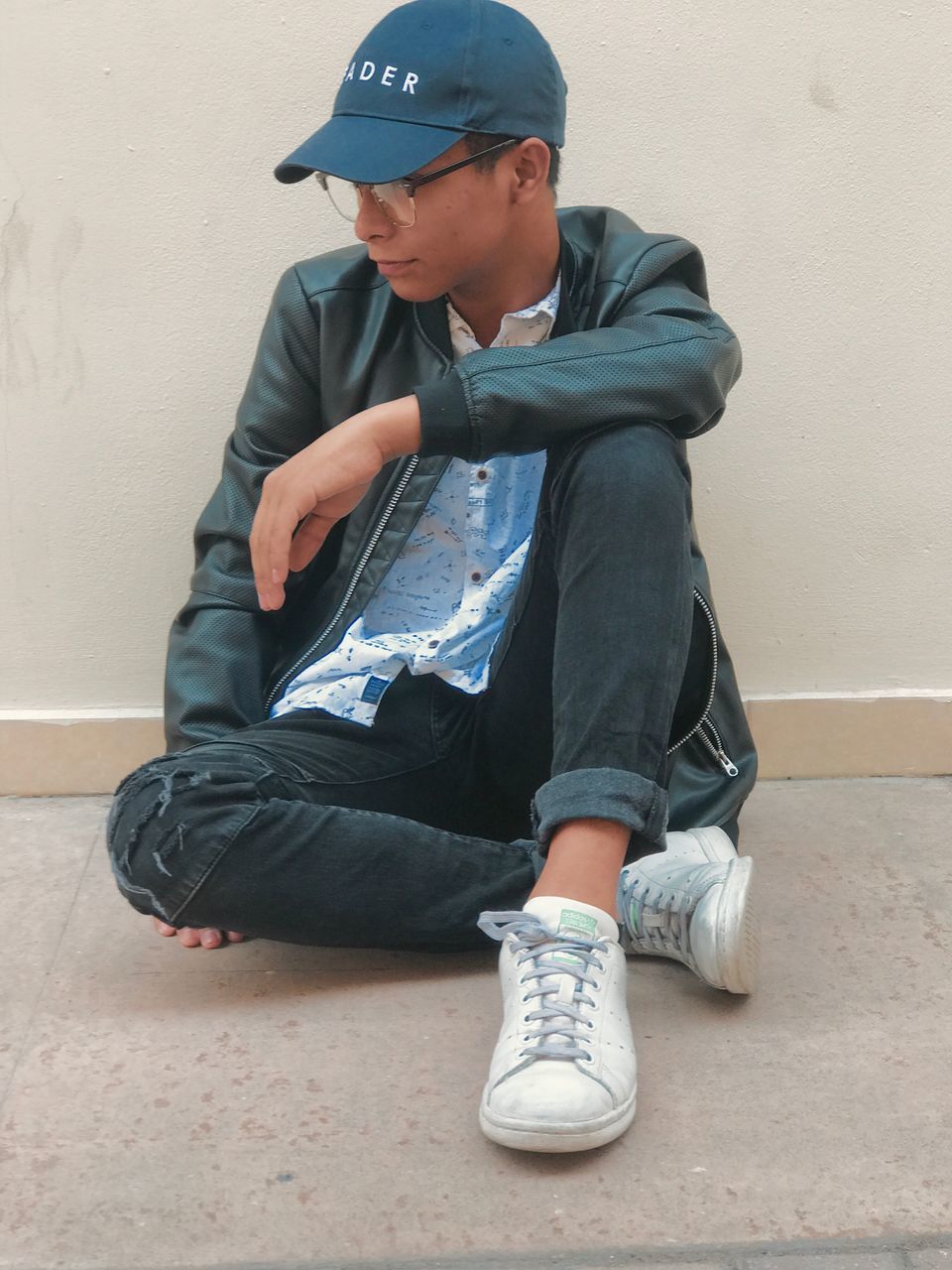 sitting, jeans, full length, child, one person, casual clothing, social issues, denim, shoe, lifestyles, people, childhood, leisure activity, one boy only, city, baseball cap, human body part, steps, day, outdoors, children only, real people, human leg, adult