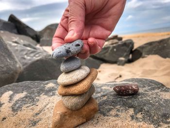 Close-up of hand holding pebbles on rock