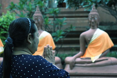 Woman praying by buddha statues