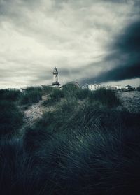 Lighthouse on field against sky