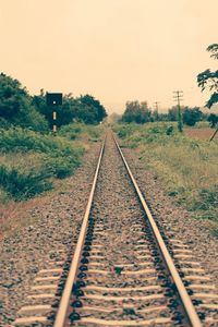 Railway tracks on field against clear sky