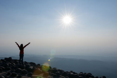 Rear view of silhouette person standing on mountain against sky