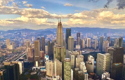 Aerial view of city buildings against cloudy sky