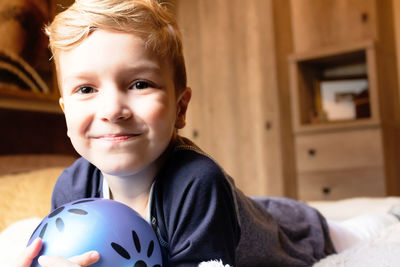 Happy little boy lying down on bed and looking at camera.