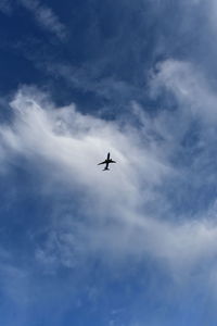 Low angle view of silhouette airplane against sky