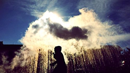 Silhouette of woman standing on field against cloudy sky