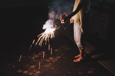 Man with woman holding sparkler on footpath at night