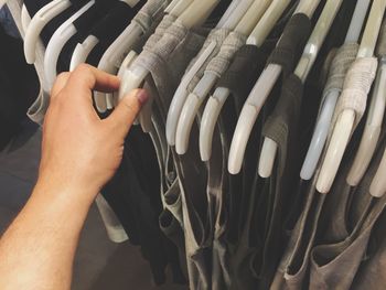 Cropped hand of woman choosing dress at store