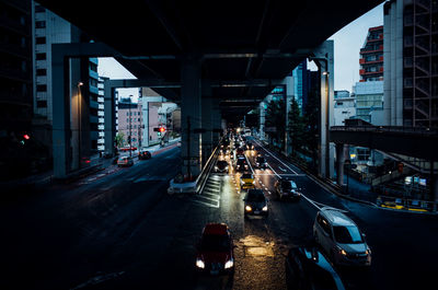 Cars on road under bridge in city at dusk