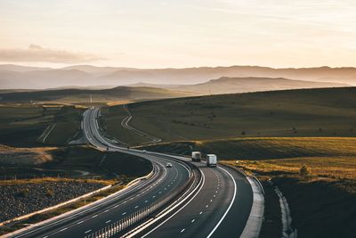 Road leading towards mountains against sky during sunset