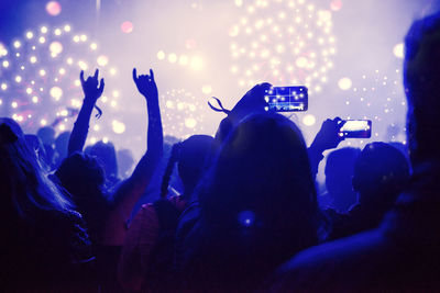 Silhouette people at music festival against firework at night