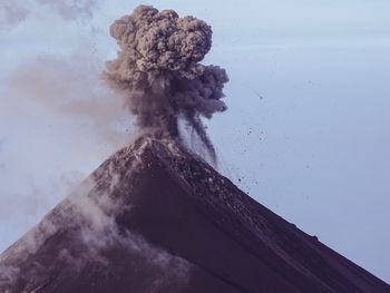 Low angle view of smoke emitting from volcanic mountain against sky