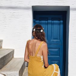 Rear view of woman standing against house