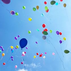 Low angle view of colorful helium balloons moving up in sky