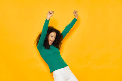 Young woman standing against yellow background