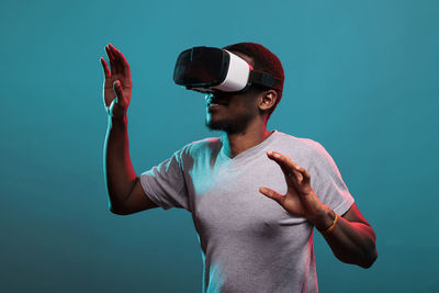 Man gesturing wearing virtual reality headset against colored background