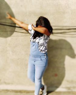 Full length of woman dancing against wall